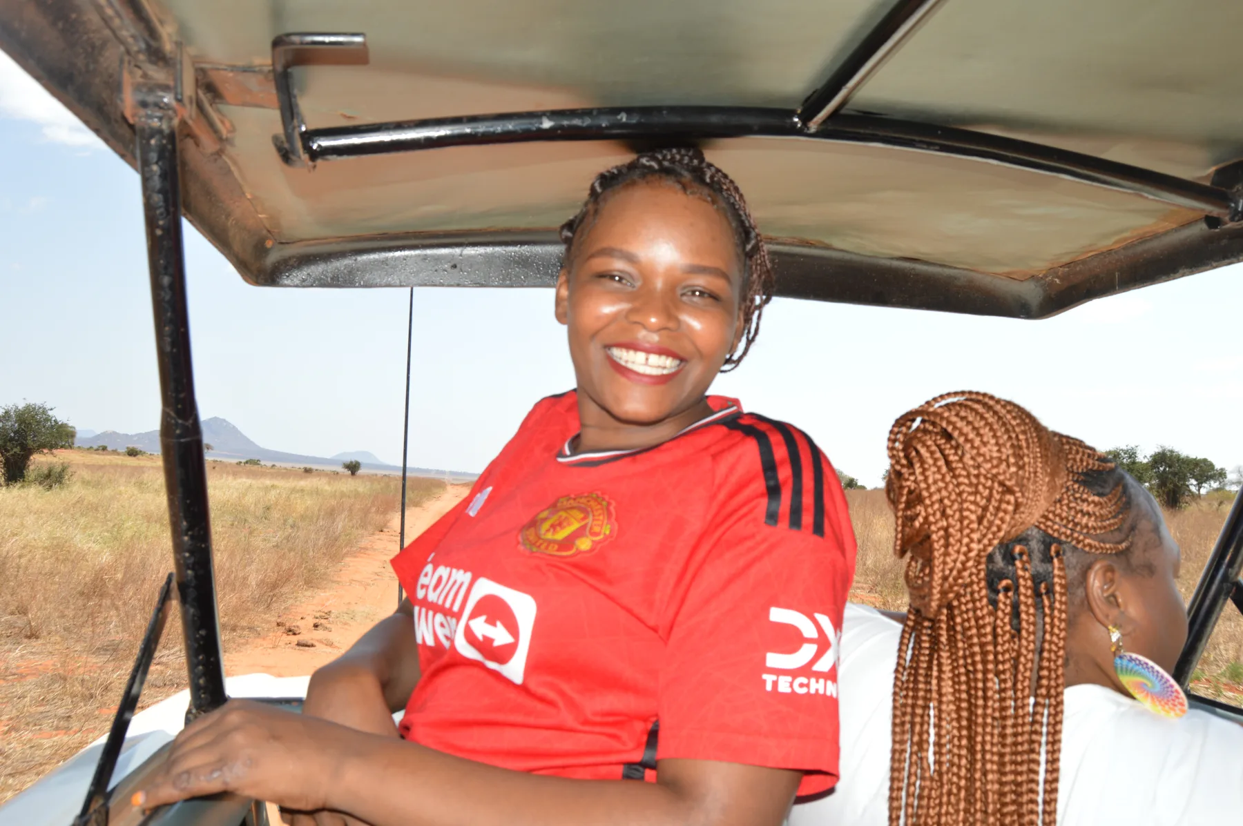 A guest smiling from the roof hatch of a safari van